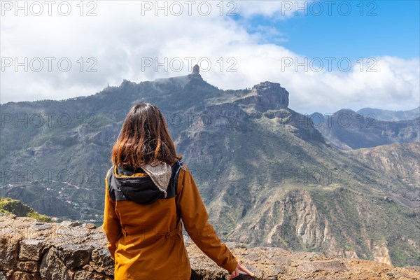 A tourist woman looking at Roque Nublo from a viewpoint on the mountain. Gran Canaria, Spain, Europe