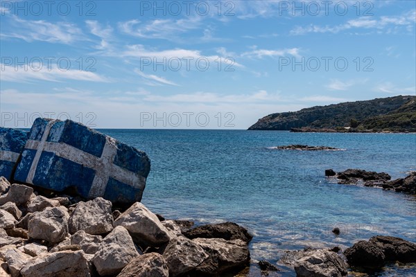 Greece flag painted on the rocks on the sea shore