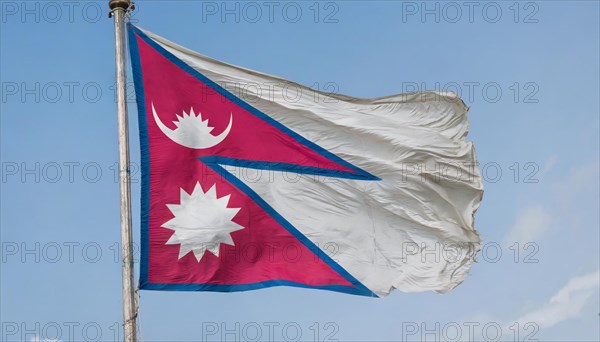 The flag of Nepal, fluttering in the wind, isolated against a blue sky