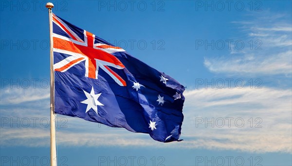 The flag of Australia flutters in the wind, isolated against a blue sky