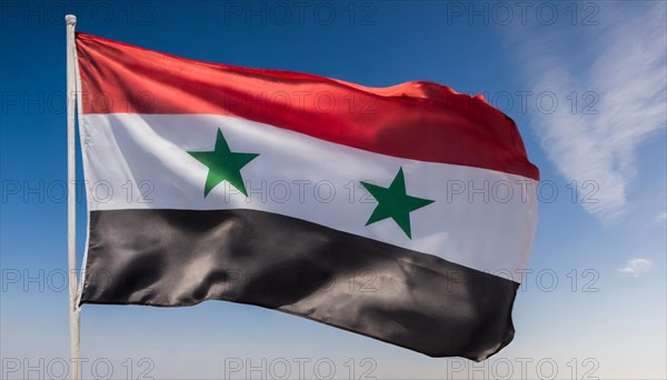 The flag of Syria flutters in the wind, isolated against a blue sky