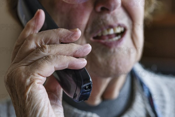 Mouth, hands and telephone receiver of a senior citizen making a phone call, close-up, Cologne, North Rhine-Westphalia, Germany, Europe