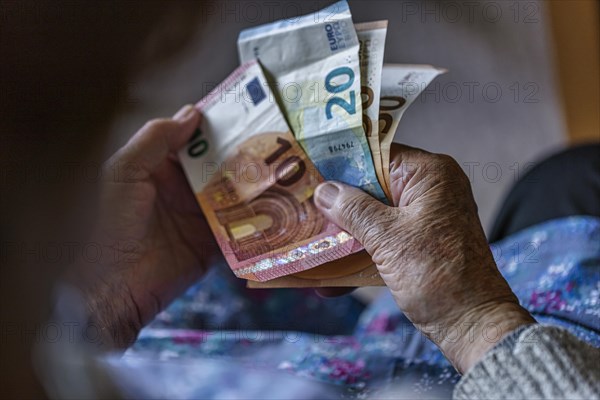 Senior citizen with wrinkled hands counts her money at home in her flat and holds banknotes in her hand, Cologne, North Rhine-Westphalia, Germany, Europe