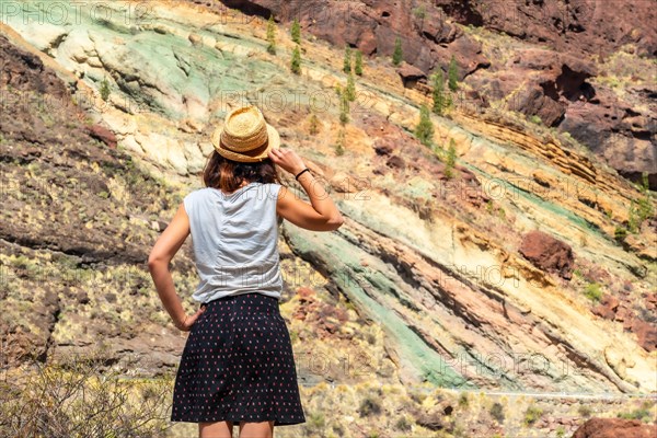 A tourist woman at the Natural Monument Azulejos de Veneguera or Rainbow Rocks in Mogan, Gran Canaria