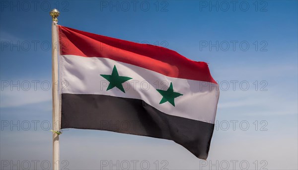 The flag of Syria flutters in the wind, isolated against a blue sky