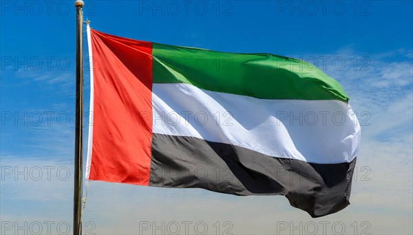 The flag of United Arab Emirates, fluttering in the wind, isolated, against the blue sky