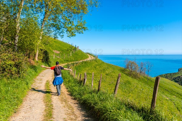 A male tourist trekking on the climb to the flysch of Zumaia, Gipuzkoa. Basque Country