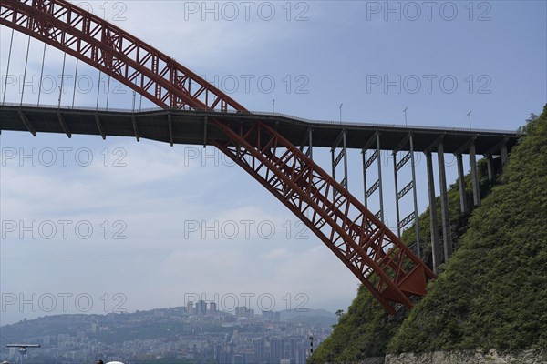 Chongqing, Chongqing Province, A high red bridge spans a river, with a city in the sunny background, Chongqing, Chongqing Province, China, Asia
