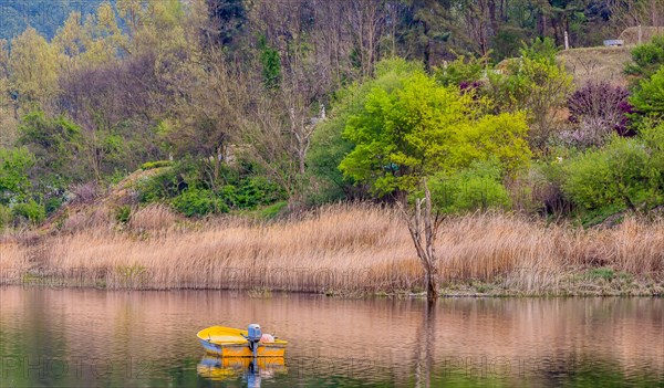 Small yellow metal fishing boat with small engine mount floating peacefully on a lake in South Korea