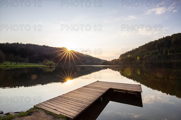 Lake at sunset. Beautiful landscape, taken from the shore of a reservoir. Situated in the middle of the forest and surrounded by nature, the reservoir offers a great atmosphere. Marbach Reservoir, Odenwald, Hesse, Germany, Europe