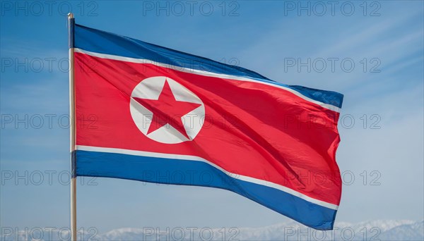 The flag of North Korea flutters in the wind, isolated against a blue sky