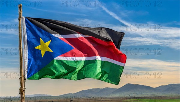 The flag of South Sudan, fluttering in the wind, isolated, against the blue sky