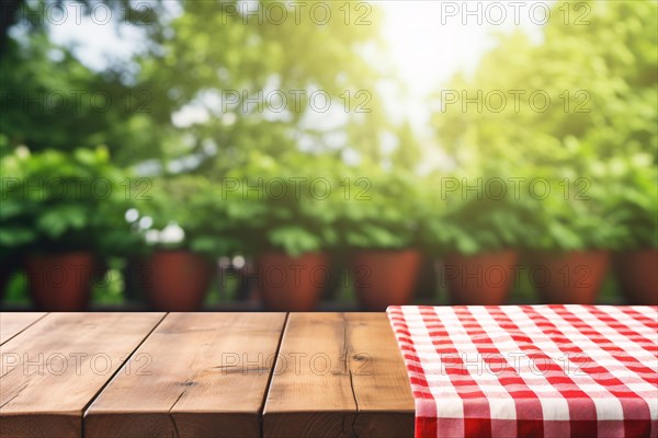 Empty wooden table with red and white checkered tablecloth in front of blurry background with potted plants in garden. KI generiert, generiert, AI generated