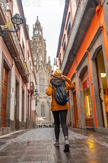 A tourist woman walking along a beautiful street next to the Church of San Juan Bautista, Arucas Cathedral, Gran Canaria, Spain, Europe