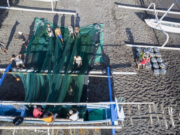 Fishermen unload their catch from their outrigger boat in the morning. Amed, Karangasem, Bali, Indonesia, Asia