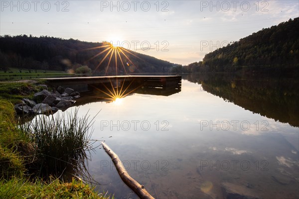 Lake at sunset. Beautiful landscape, taken from the shore of a reservoir. Situated in the middle of the forest and surrounded by nature, the reservoir offers a great atmosphere. Marbach Reservoir, Odenwald, Hesse, Germany, Europe