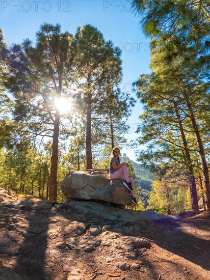 A woman sitting on a stone while hiking to Roque Nublo in Gran Canaria, Canary Islands