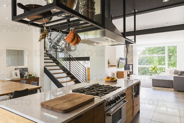 American walnut wood island with quartzite countertop and built-in gas stove in the kitchen inside modern cube style home, Quebec, Canada, North America