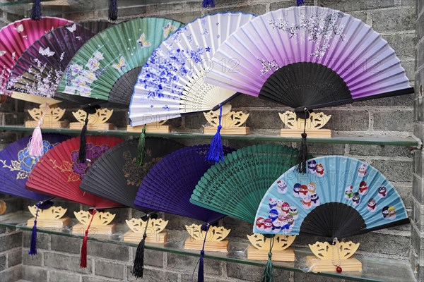 Stroll through the restored Tianzifang district, A selection of colourful, decorative fans displayed on a wall as souvenirs, Shanghai, China, Asia