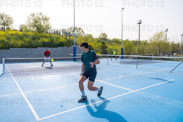 Sportive young friends working out playing pickleball in an outdoor facility
