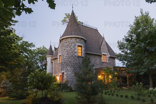 2006 reproduction of a 16th century grey stone and mortar Renaissance castle style residential home facade at dusk in summer, Quebec, Canada, North America