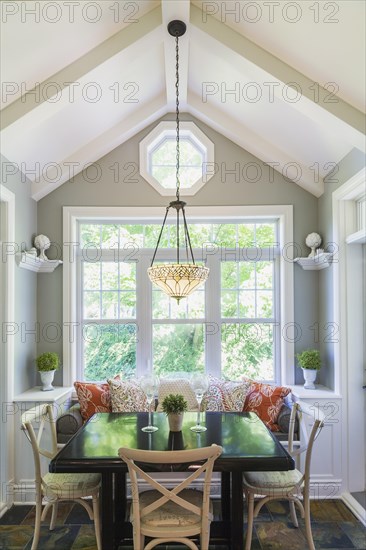 Wooden breakfast table with sitting bench and chairs in the kitchen with earth tone slate flooring inside a contemporary cottage style home, Quebec, Canada. This image is property released. PR0062