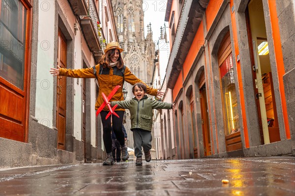 A mother playing with her son on a street near the Church of San Juan Bautista, Arucas Cathedral, Gran Canaria, Spain, Europe