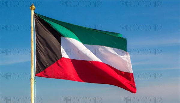 The flag of Kuwait flutters in the wind, isolated against a blue sky