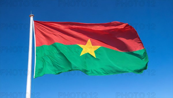 The flag of Burkina Faso flutters in the wind, isolated against the blue sky