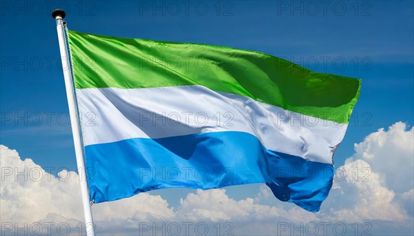 The flag of Sierra Leone, fluttering in the wind, isolated, against the blue sky