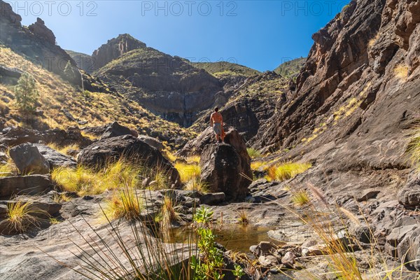 A hiker on the river on the climb to Charco Azul in the Podemos to Agaete in Gran Canaria, Canary Islands
