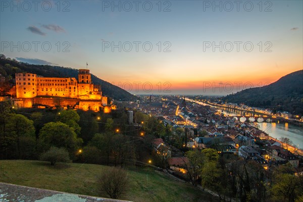 View over an old town with castle or palace rune in the evening at sunset. This town lies in a river valley of the Neckar, surrounded by hills. Heidelberg, Baden-Wuerttemberg, Germany, Europe