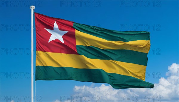 The flag of Togo flutters in the wind, isolated against a blue sky