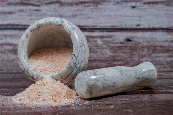 Himalayan pink salt in a ceramic mortar on a wooden table with a copy space