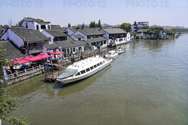 Excursion to Zhujiajiao Water Village, Shanghai, China, Asia, wooden boat on canal with views of historic architecture, modern watercraft and buildings along a clear river, Asia