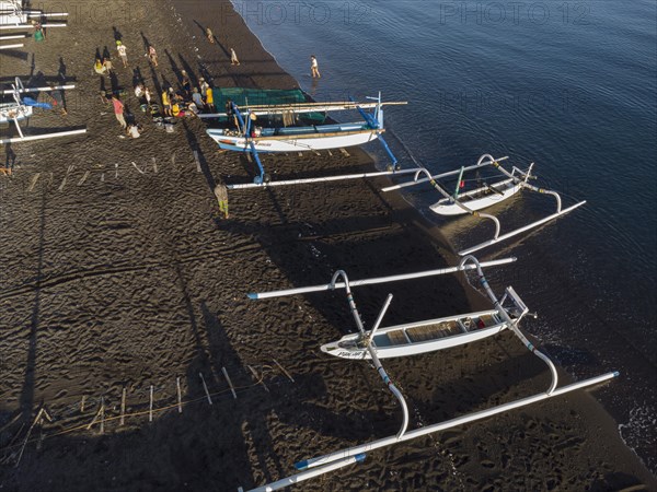 Fishermen unload their catch from their outrigger boat in the morning. Amed, Karangasem, Bali, Indonesia, Asia