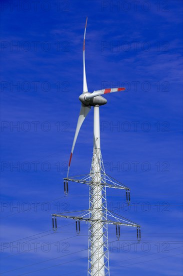 Electricity pylon with high-voltage lines and wind turbine at the Avacon substation Helmstedt, Helmstedt, Lower Saxony, Germany, Europe