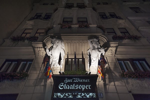 Entrance portal with atlant and caryatid on the building of the Vienna State Opera in the night lighting, Vienna, Austria, Europe