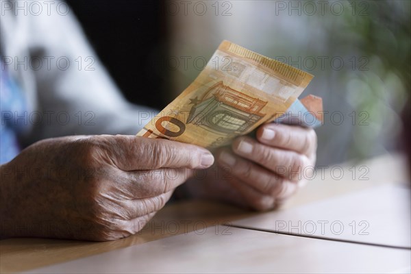 Senior citizen with wrinkled hands counts her money at home in her flat and holds banknotes in her hand, Cologne, North Rhine-Westphalia, Germany, Europe