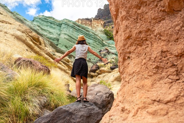 A tourist woman enjoying the natural monument at the Azulejos de Veneguera or Rainbow Rocks in Mogan, Gran Canaria