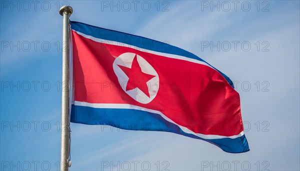 The flag of North Korea flutters in the wind, isolated against a blue sky