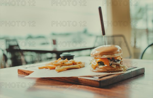 Traditional hamburger with fries served on a restaurant table. Appetizing burger with fries served on a wooden table