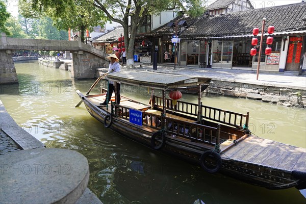 Excursion to Zhujiajiao water village, Shanghai, China, Asia, Person in traditional clothes steering a boat through a city canal, Asia