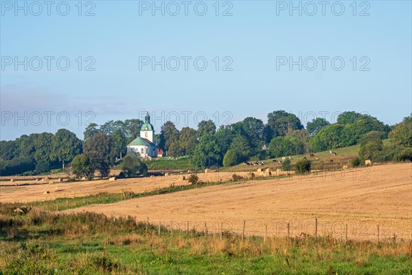 View at a rural landscape view with fields and a church in the swedish countryside, Sloeta, Falkoeping, Sweden, Europe
