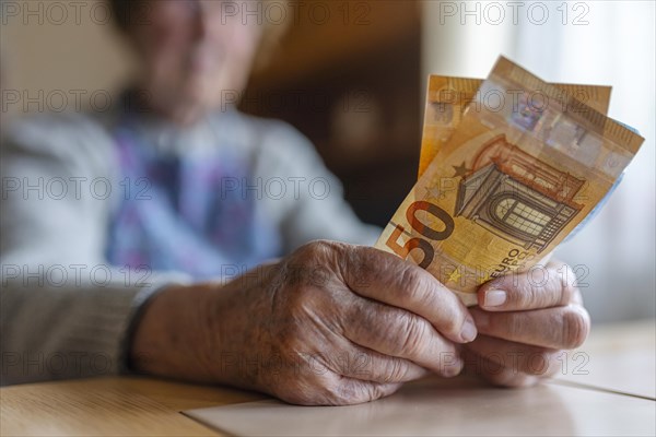 Senior citizen with wrinkled hands counts her money at home in her flat and holds banknotes in her hand, Cologne, North Rhine-Westphalia, Germany, Europe