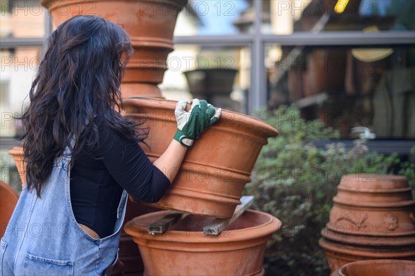 A focused woman arranging pots in a pottery workshop