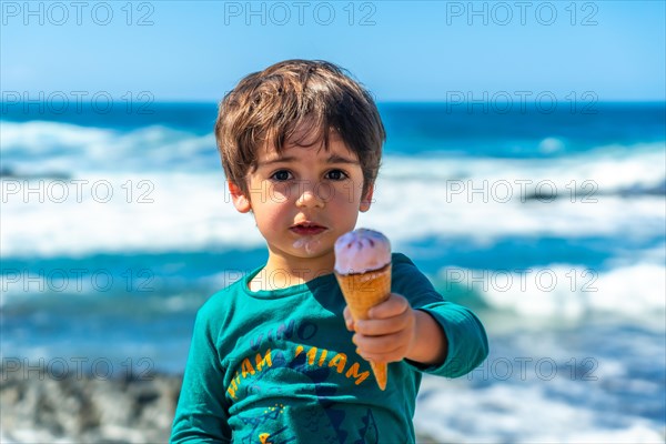 Portrait of a boy eating a delicious ice cream by the sea in summer. Family vacation concept