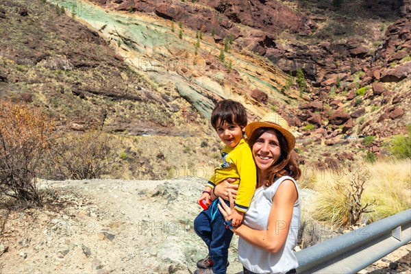 Family of mother and son enjoying at the Natural Monument Azulejos de Veneguera or Rainbow Rocks in Mogan, Gran Canaria