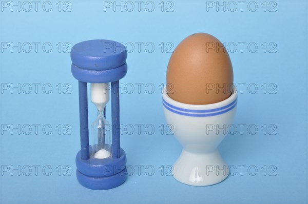 Boiled egg and hourglass on a blue background