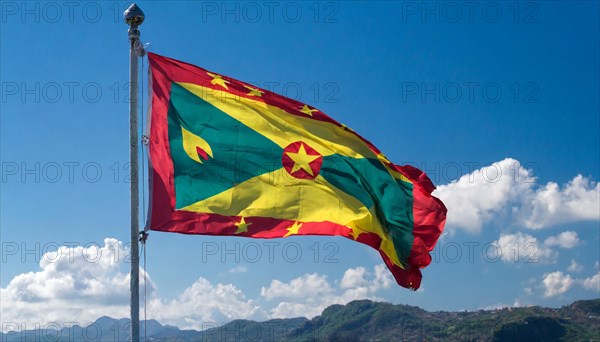 The flag of Grenada, Caribbean, flutters in the wind, isolated, against the blue sky